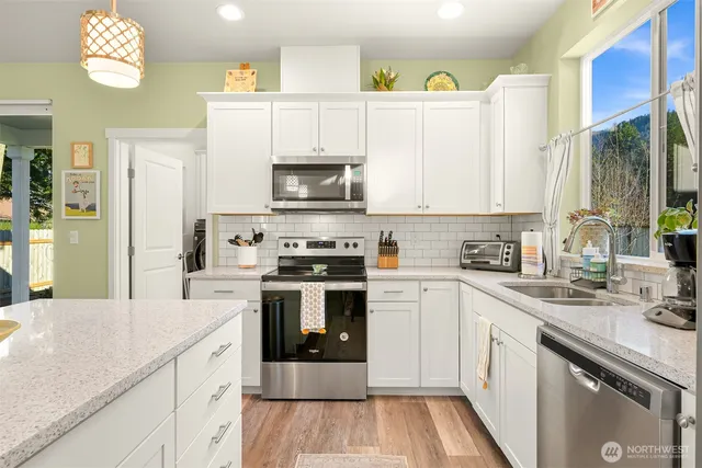 a kitchen with a sink cabinets stainless steel appliances and a window