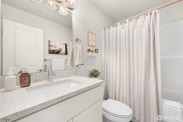 a bathroom with a granite countertop sink a toilet and shower curtain