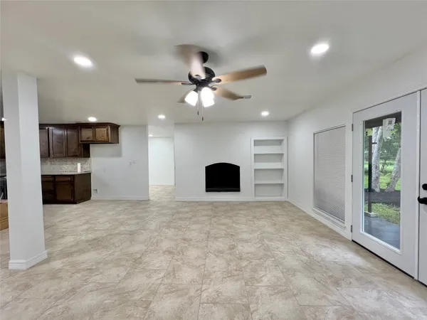 a view of an empty room with a kitchen and a window