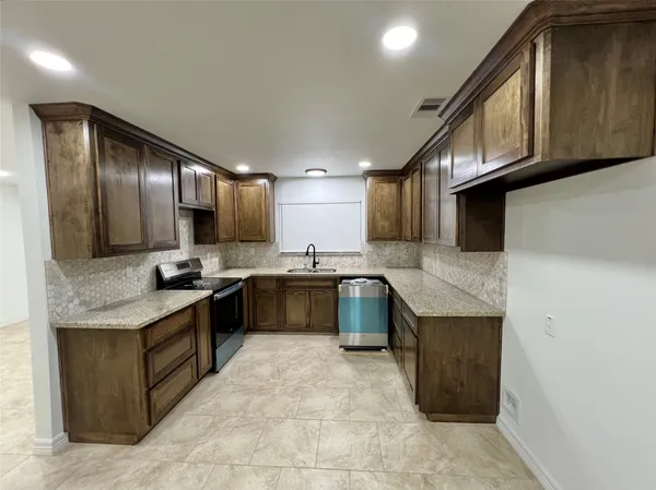 a large kitchen with stainless steel appliances granite countertop a stove and a sink