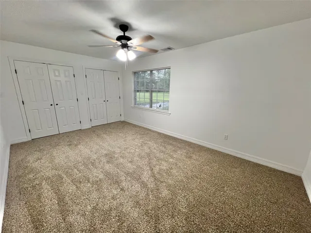 an empty room with a chandelier fan and windows