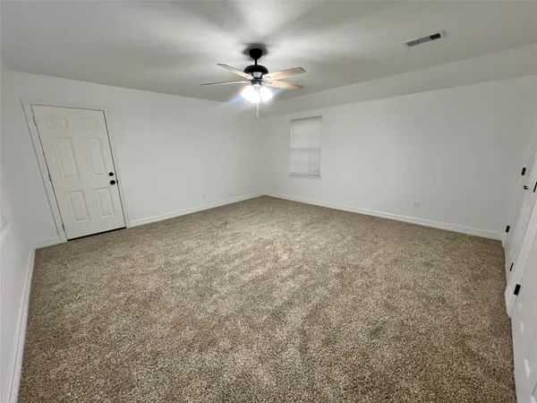 an empty room with a chandelier fan and windows