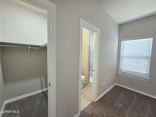 a view of an empty room with closet and a window