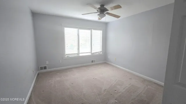 an empty room with a window and a fan