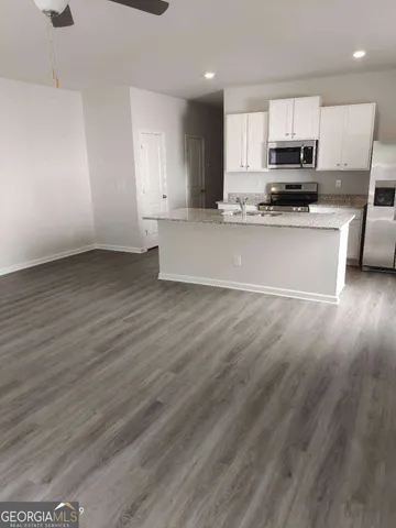 a view of kitchen with granite countertop stainless steel appliances refrigerator sink and microwave