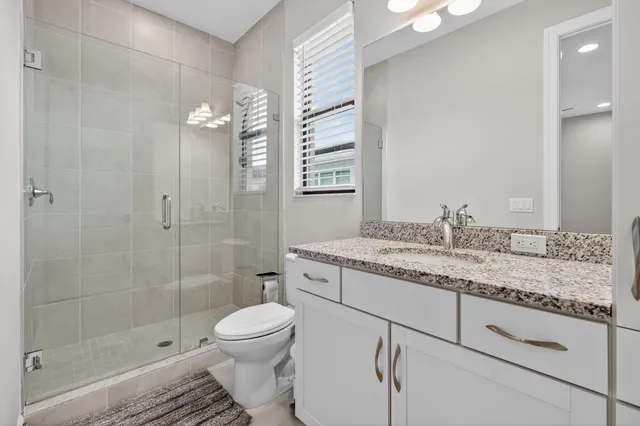 a bathroom with a granite countertop sink toilet a mirror and shower