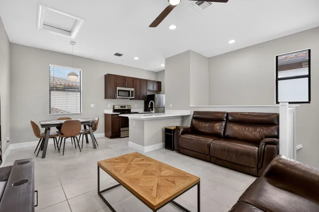 a living room with furniture a computer on a desk and kitchen view