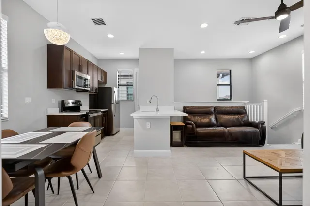 a living room with stainless steel appliances furniture a flat screen tv and kitchen view