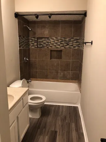 a bathroom with a granite countertop bathtub shower sink vanity and toilet