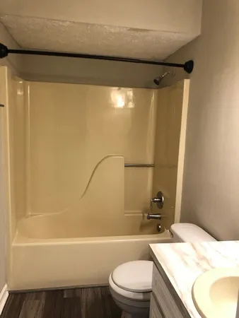 a view of an empty room with wooden floor and a chandelier fan