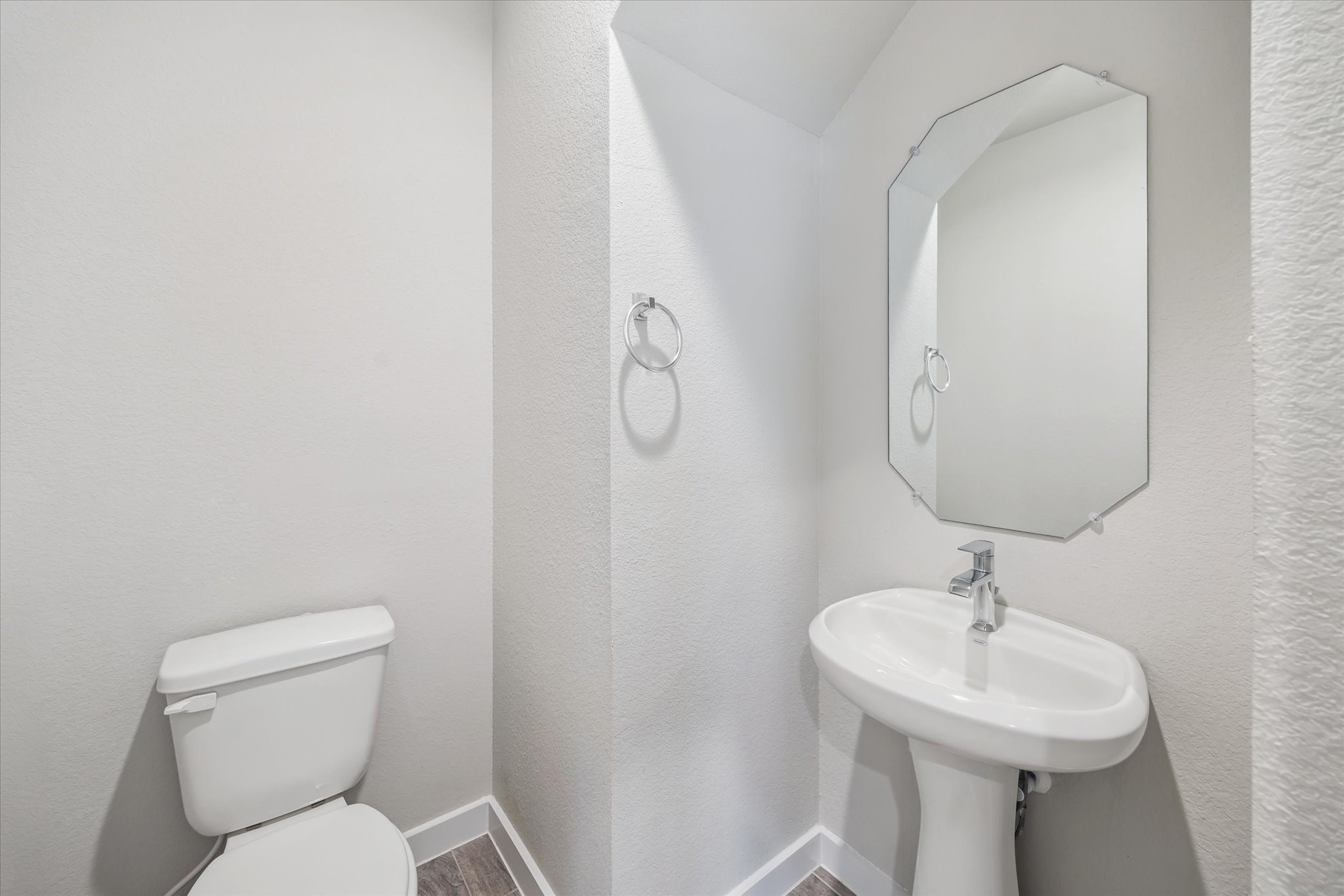 2138 Reed Cave Lane Spring, TX 77386 - Photo 10 of 23 This is a compact, modern half-bathroom featuring a pedestal sink, a toilet, and a stylish mirror. The space is bright and clean with neutral wall colors and a minimalist design.