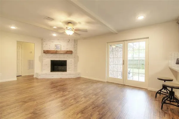 a view of an empty room with a window and wooden floor