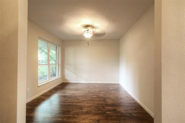 a view of an empty room with wooden floor and a window