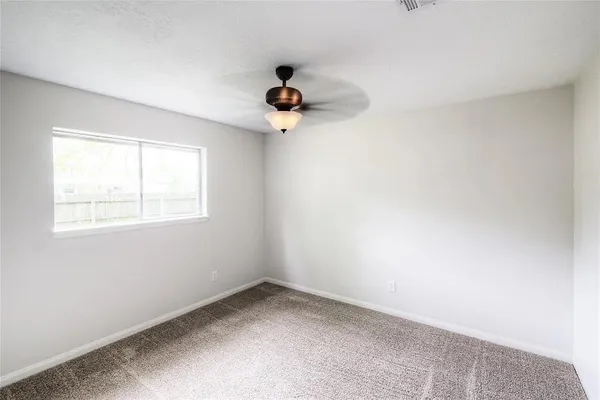an empty room with a window and a fan