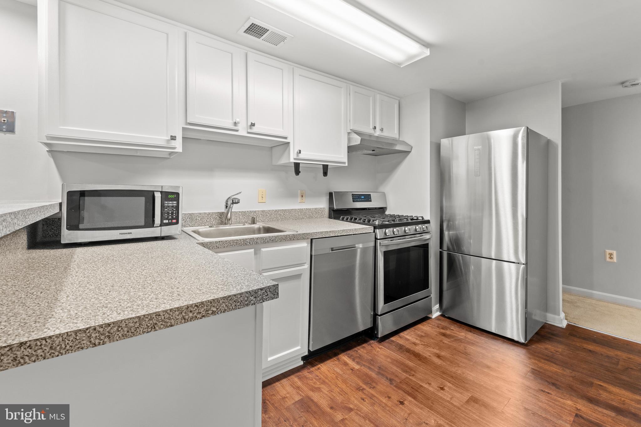 3612 Rock Creek Church Road Northwest, Unit LWR Washington, DC 20010 - Photo 4 of 19 a kitchen with a refrigerator stove and wooden cabinets