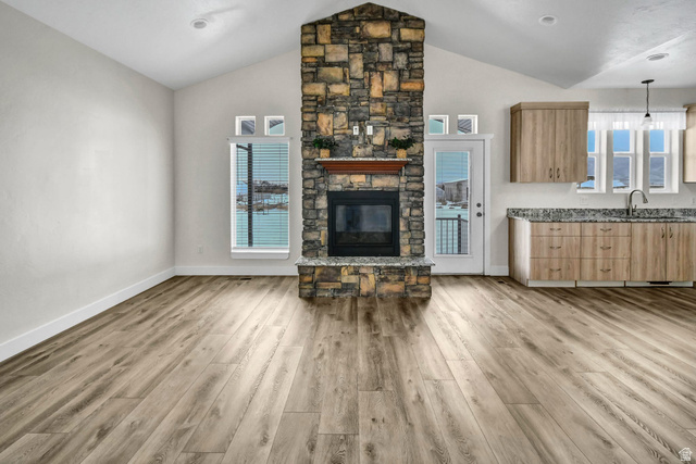 1103 North Brooklyn Road Monroe, UT 84754 - Photo 14 of 78 Living area featuring a stone fireplace, vaulted ceiling, healthy amount of natural light, and light wood-type flooring