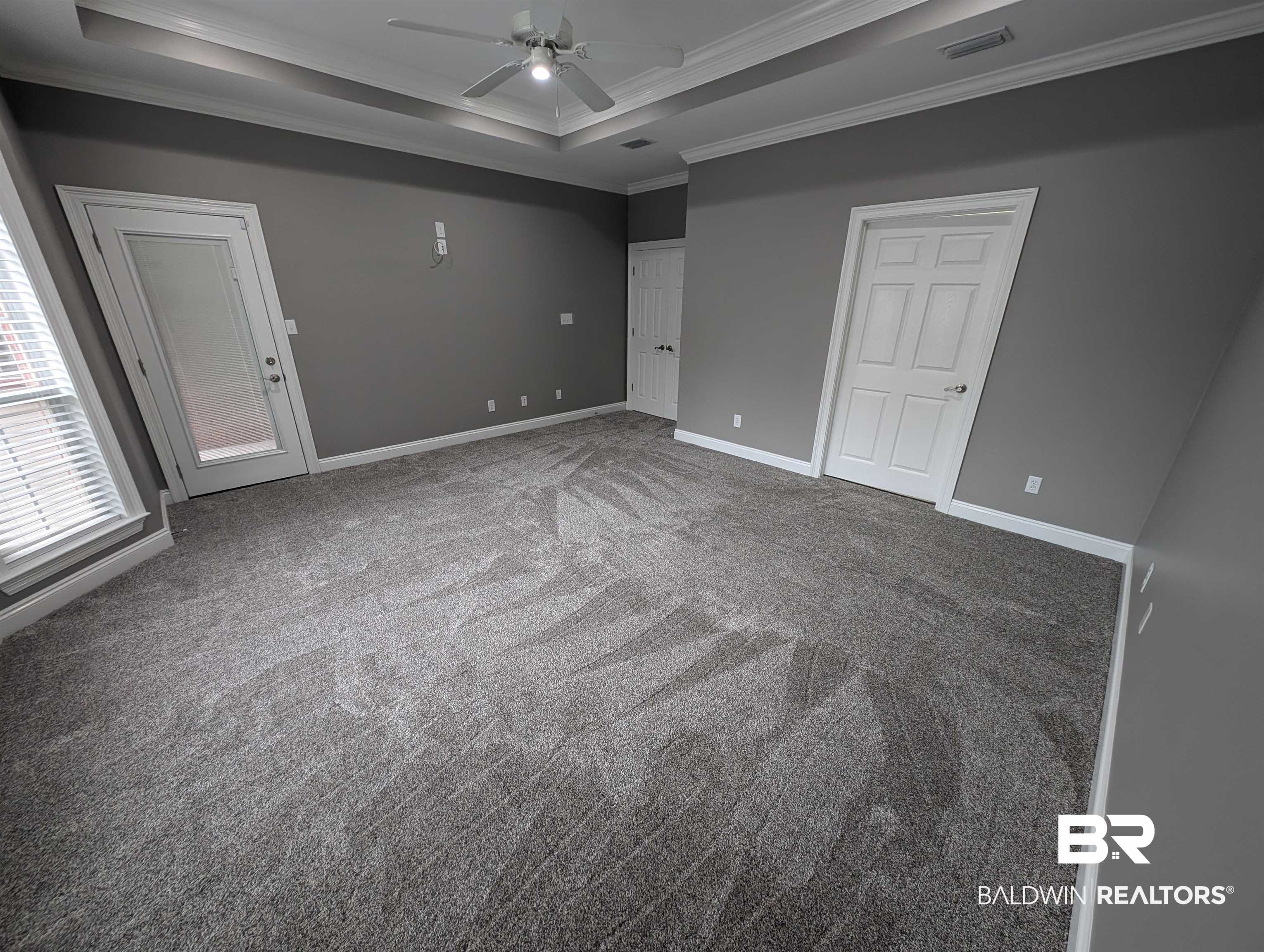 11623 Halcyon Loop Daphne, AL 36526 - Photo 54 of 90 Open primary bedroom featuring crown molding, a tray ceiling, dark colored carpet, and ceiling fan with ensuite