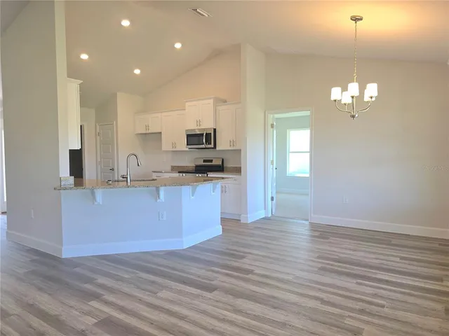 a large kitchen with kitchen island a sink dishwasher a refrigerator and a stove with wooden floor