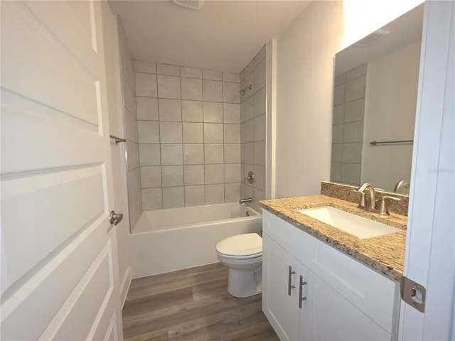 a bathroom with a granite countertop bathtub shower sink mirror vanity and toilet