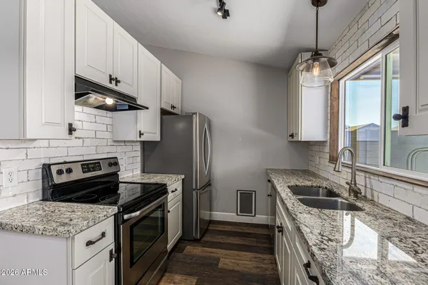 a kitchen with granite countertop a sink stove and refrigerator