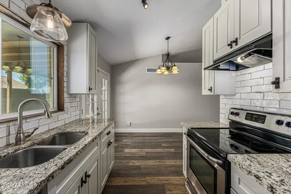 a kitchen with a sink and a stove with wooden floor