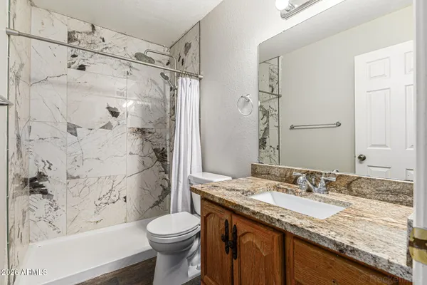a bathroom with a granite countertop sink toilet and shower