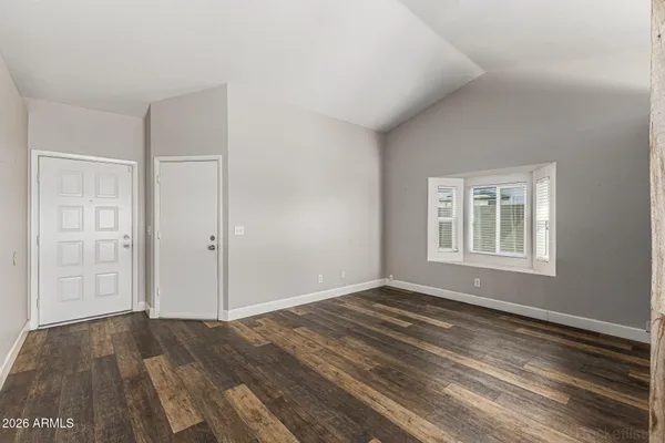 a view of an empty room with wooden floor and a window