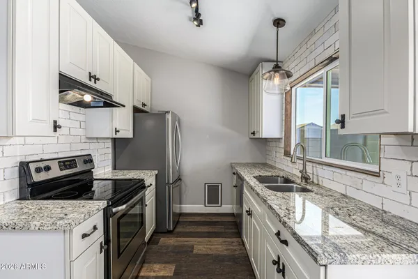 a kitchen with granite countertop a sink stove and refrigerator
