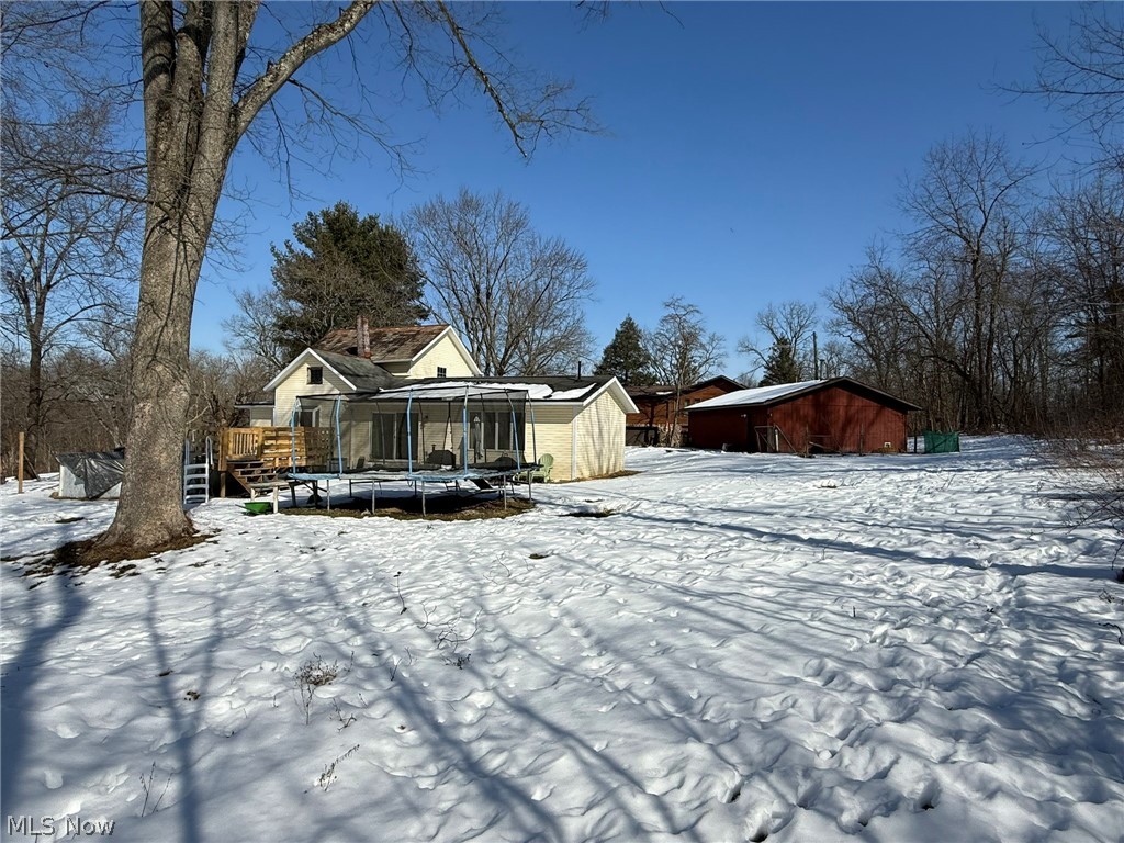 6784 Old Zoarville Road Northeast Dover, OH 44622 - Photo 47 of 50 Snow covered house featuring a trampoline, a deck, and an outbuilding