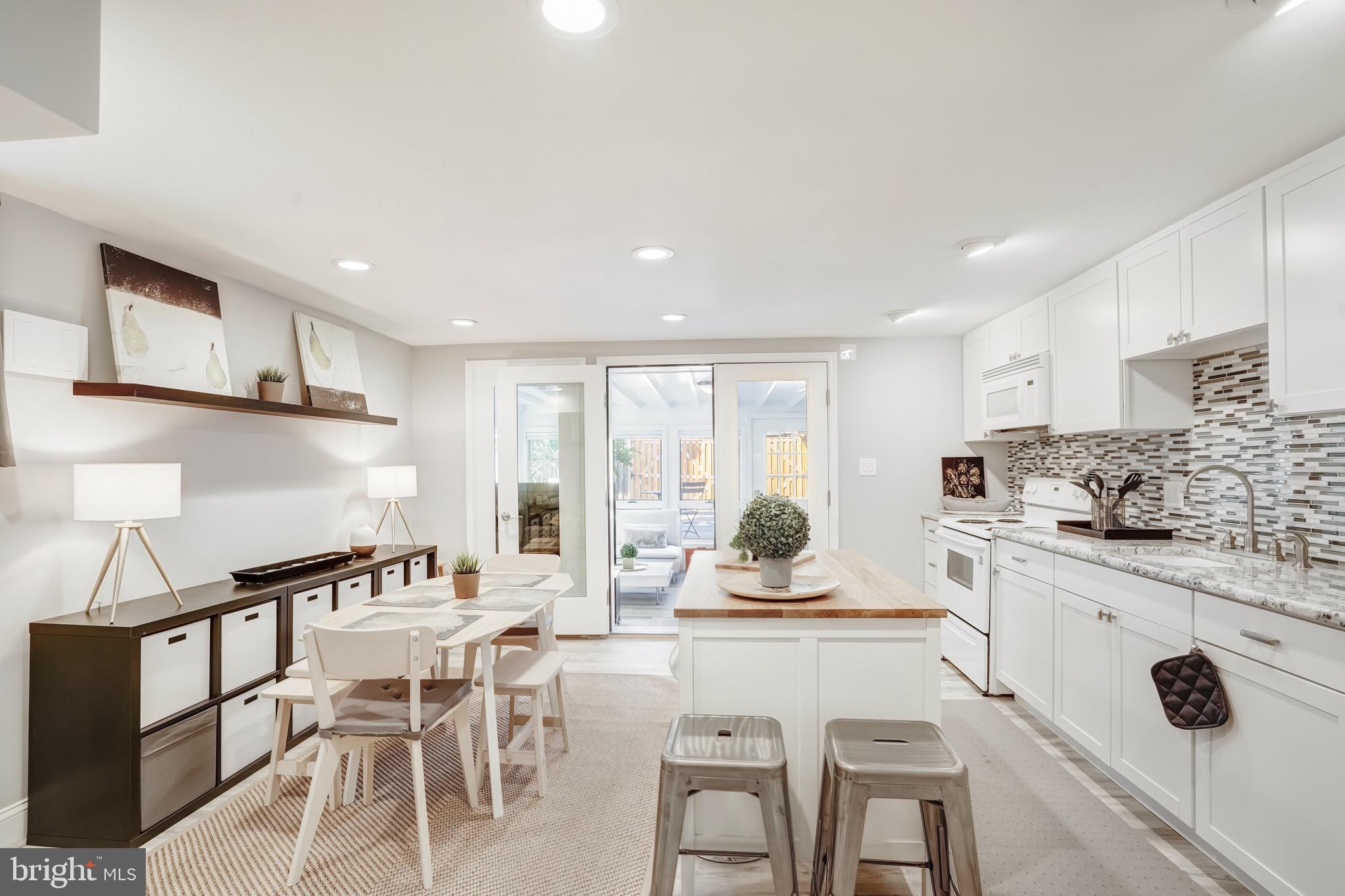 3817 Cathedral Avenue Northwest, Unit GARDEN Washington, DC 20016 - Photo 14 of 33 a kitchen with stainless steel appliances kitchen island granite countertop a stove a sink a dining table and chairs