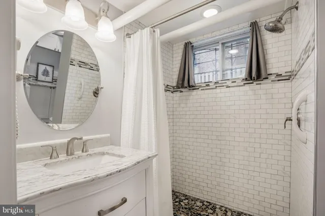 a bathroom with a granite countertop sink a mirror and shower