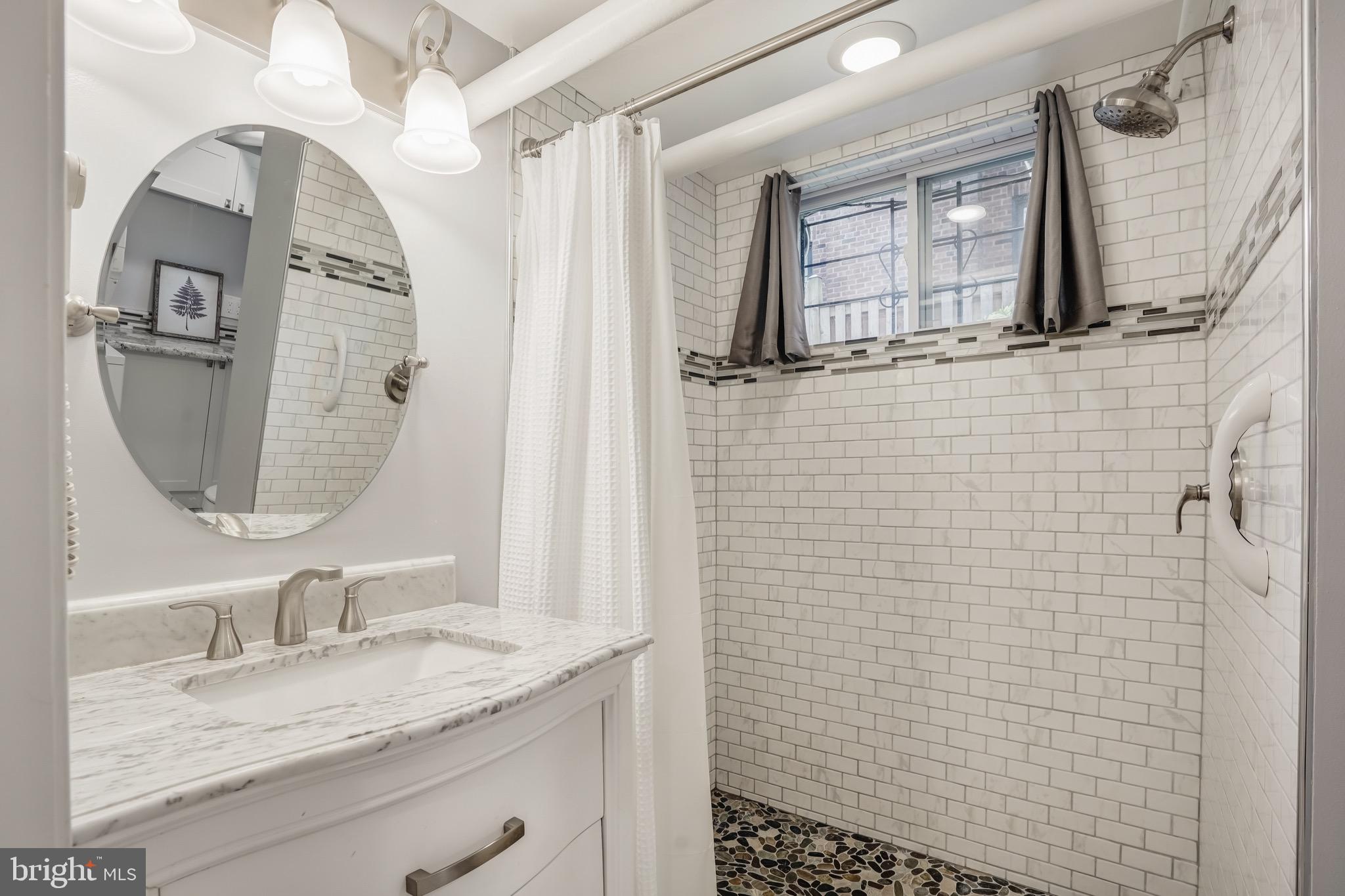 3817 Cathedral Avenue Northwest, Unit GARDEN Washington, DC 20016 - Photo 23 of 33 a bathroom with a granite countertop sink a mirror and shower
