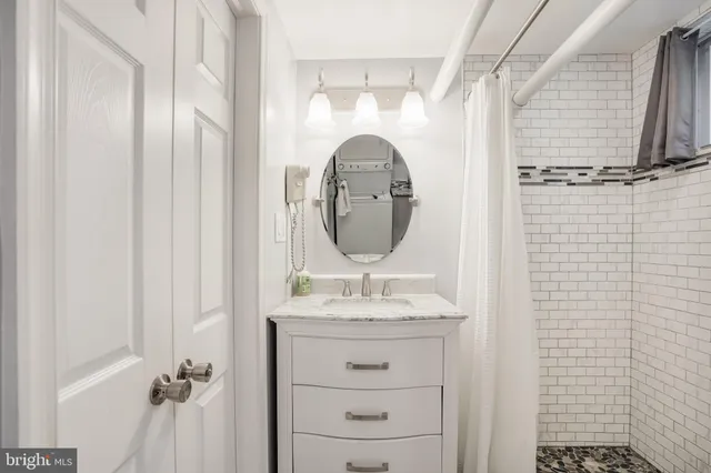 a bathroom with a granite countertop sink a mirror and shower