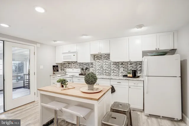 a kitchen with a refrigerator a stove a sink and white cabinets with wooden floor