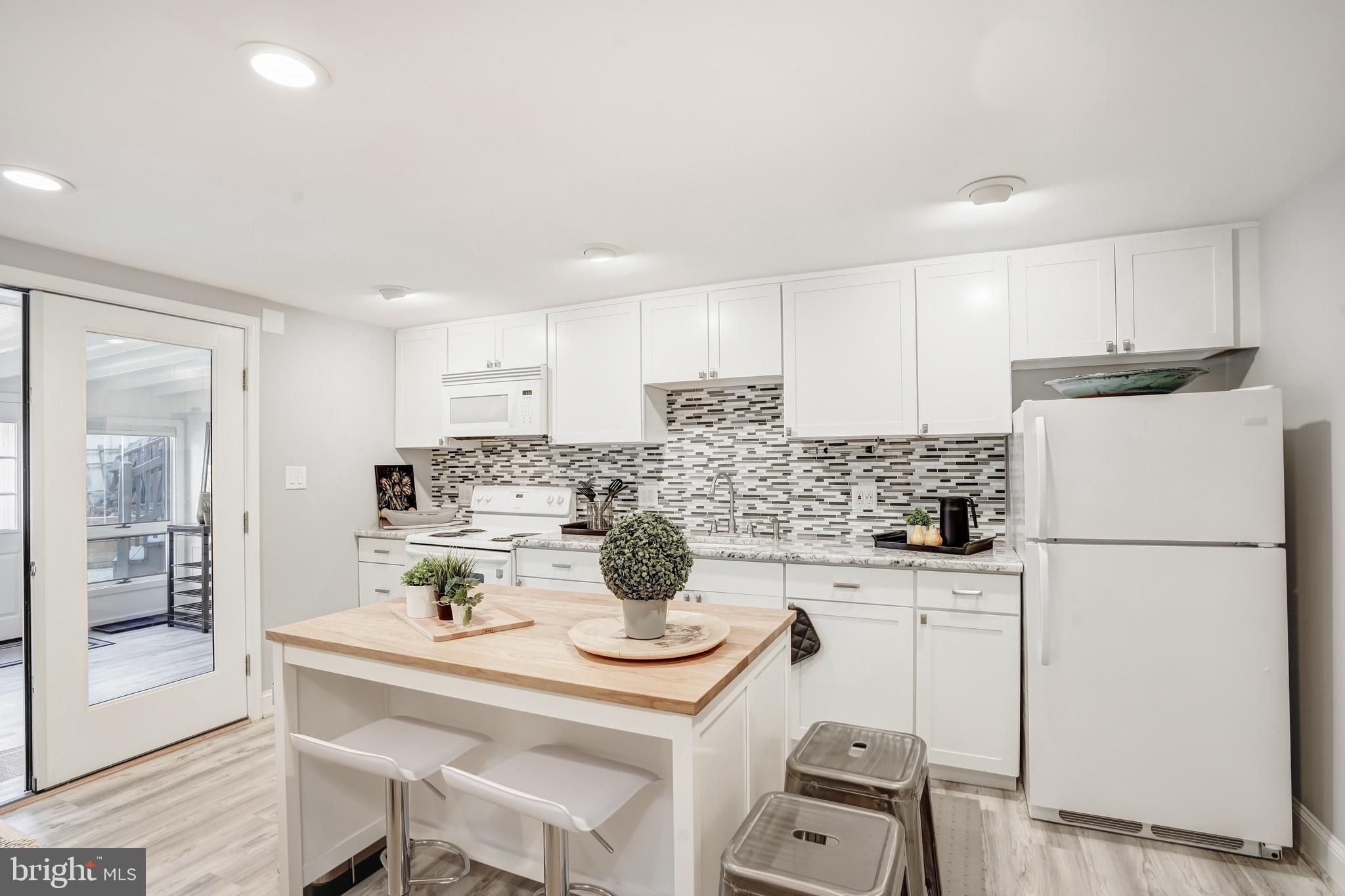 3817 Cathedral Avenue Northwest, Unit GARDEN Washington, DC 20016 - Photo 10 of 33 a kitchen with a refrigerator a stove a sink and white cabinets with wooden floor