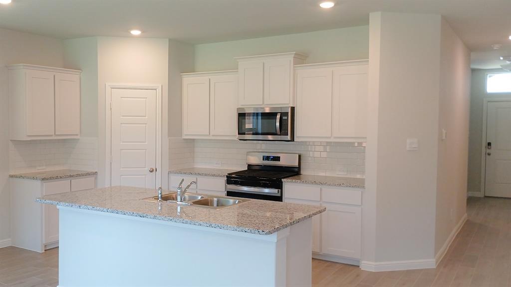 a kitchen with granite countertop a sink and a stove top oven with wooden floor