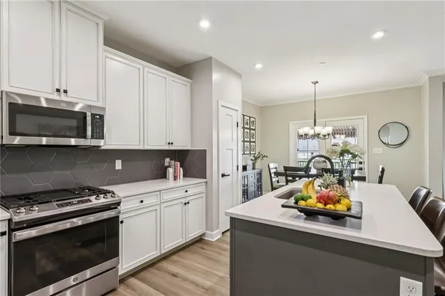 a kitchen that has a lot of white cabinets and stainless steel appliances