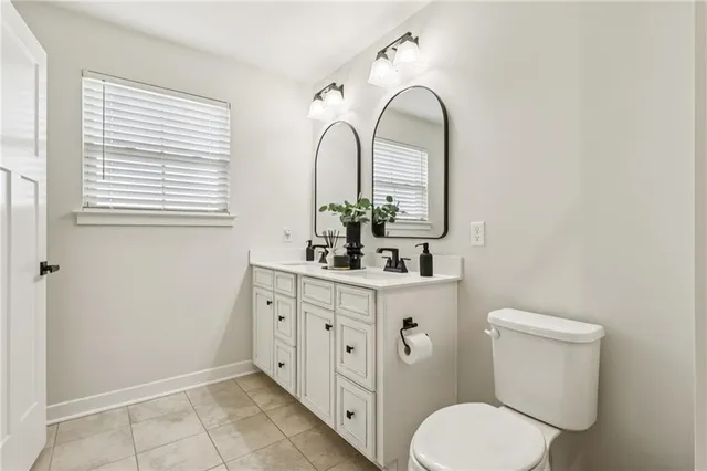 a bathroom with a double vanity sink toilet and a window