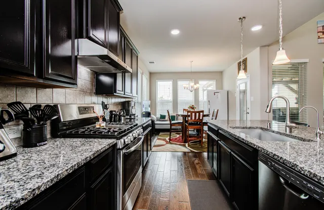 a kitchen with stainless steel appliances granite countertop a stove a sink a oven and a microwave