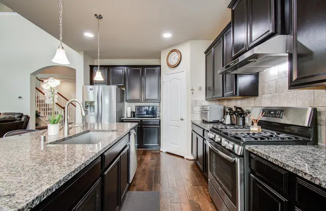 a kitchen with stainless steel appliances granite countertop a sink stove and refrigerator