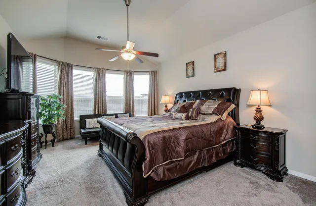a bedroom with a bed and a flat tv screen on dresser