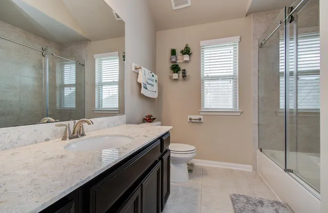 a bathroom with a granite countertop sink a toilet a mirror and window