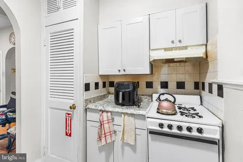 a kitchen with a stove and white cabinets