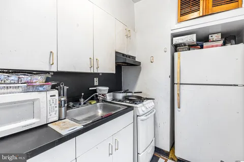 a kitchen with stainless steel appliances granite countertop a refrigerator sink stove and white cabinets