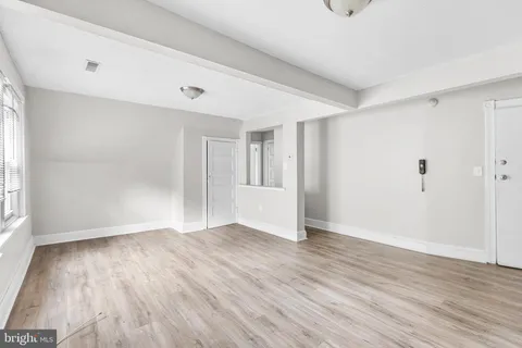 a view of an empty room with wooden floor and a window