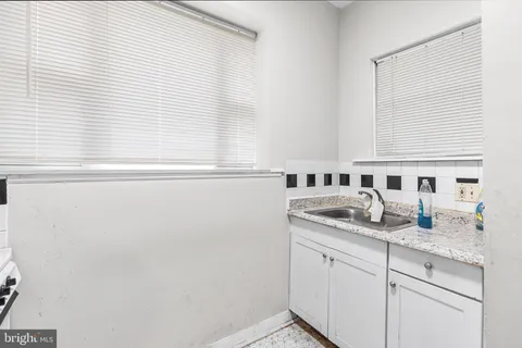 a bathroom with a granite countertop sink and a window