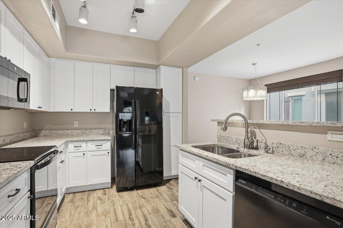 2401 East Rio Salado Parkway, Unit 1045 Tempe, AZ 85288 - Photo 14 of 41 a kitchen with a sink dishwasher a refrigerator and white cabinets with wooden floor