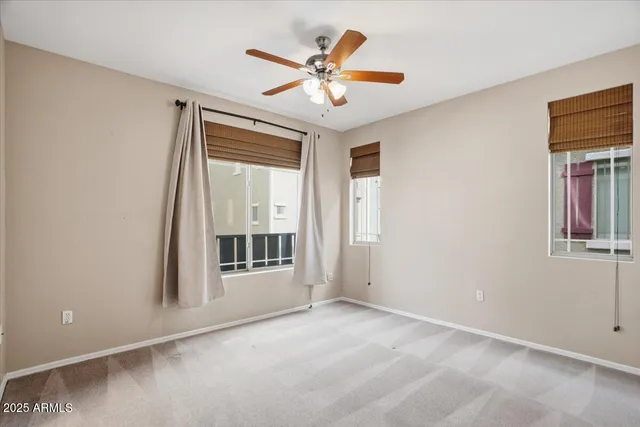 an empty room with a ceiling fan and windows