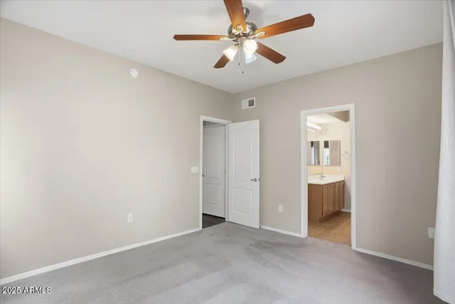 an empty room with closet and a ceiling fan