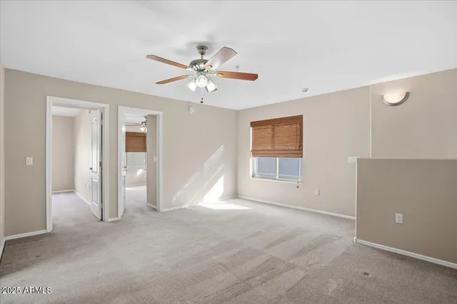 a view of a big room with windows and chandelier fan